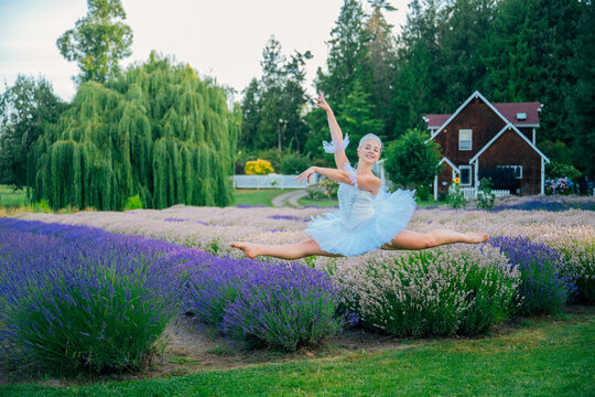 A ballerina performs a split leap outdoors