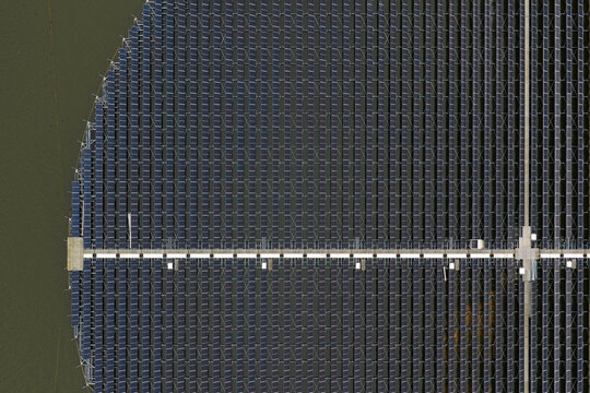 Aerial view of the circular floating solar panel installation at the PWN drinking water treatment facility, with rows of photovoltaic modules in Andijk, Noord-Holland, Netherlands.