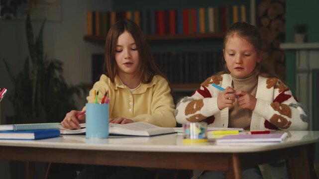 Children prepare for school test with books, writing notes in notebooks at home