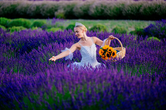 A woman in a white dress picks lavender flowers in a field in WA, USA