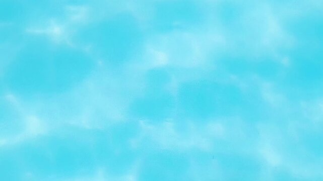 Soft abstract view of turquoise swimming pool water with gentle blurred ripples, shimmering sunlight reflections, and calm blue aquatic texture.