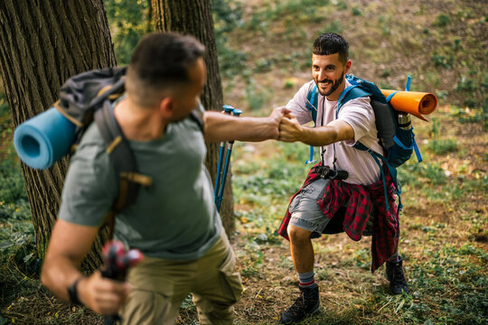Hiker reaching out to help a companion on a forest trail