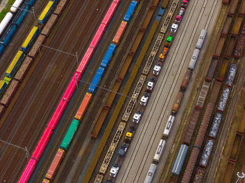 Aerial view of colorful freight trains and cargo containers parked on parallel railway tracks at a busy rail yard in Breclav, South Moravian Region, Czechia.