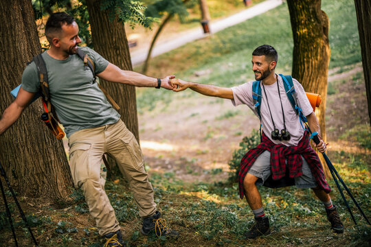 Hiker reaching out to help a companion across a forest trail