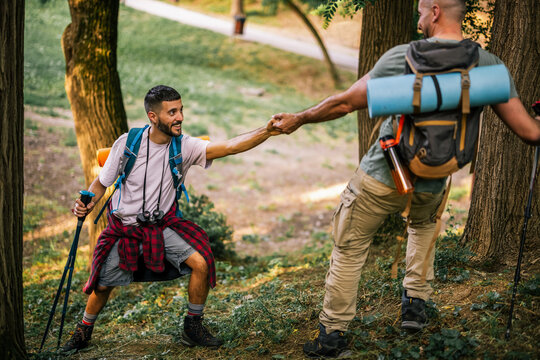 Hiker helping a companion up a forest trail during a hike
