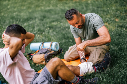 Hiker treating a companion's injured ankle with a bandage outdoors
