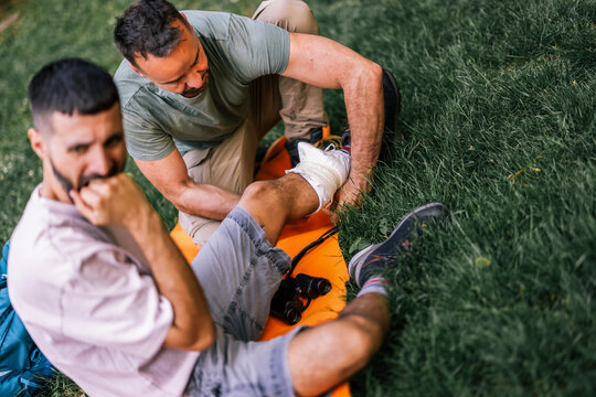 Hiker helping an injured companion while treating his ankle outdoors