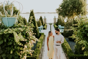 Couple walks hand in hand through a beautiful garden at sunset © BGStock72