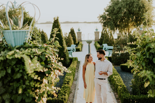 Couple walks hand in hand through a beautiful garden at sunset