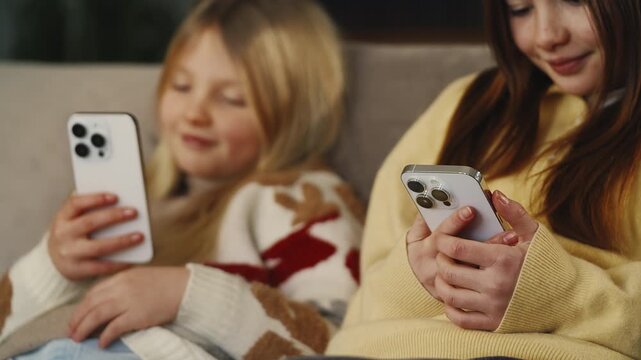 Two sisters type on their phones, prolonged exposure to digital devices