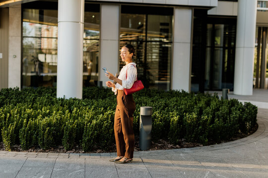 Korean woman enjoying a sunny day while taking photos in a modern city area