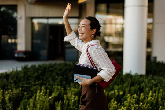 Korean woman happily greets the day while walking in an urban setting