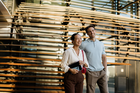 Korean woman and Caucasian man enjoying sunny day at modern architecture