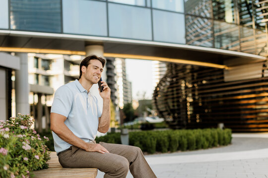 Man enjoying a sunny day while talking on the phone in an urban setting