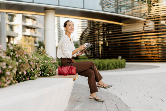 Korean woman enjoys a quiet moment while sketching in a modern city setting