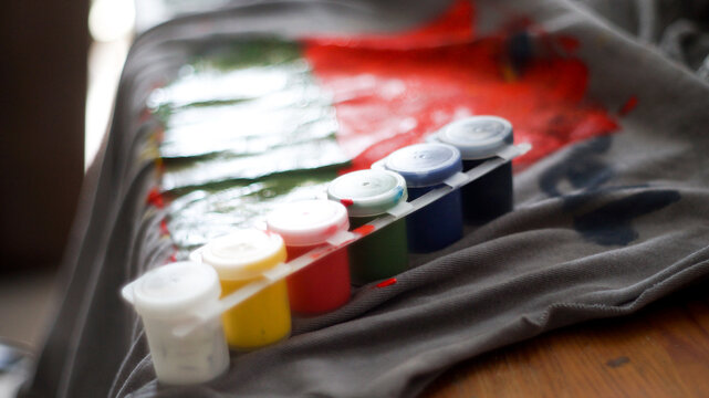 Creative mess with messy paint brushes and multi-colored paints on artist tabletop