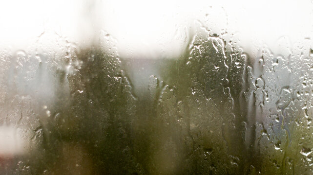 Raindrops on window glass surface as abstract moody background