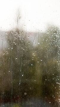 Raindrops on window glass surface as abstract moody background