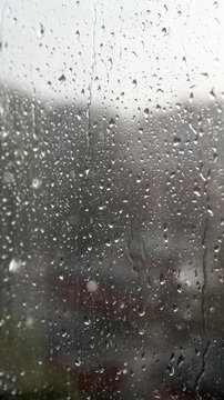 Raindrops on window glass surface as abstract moody background