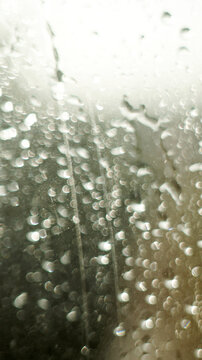 Raindrops on window glass surface as abstract moody background