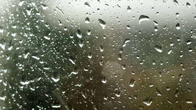 Raindrops on window glass surface as abstract moody background