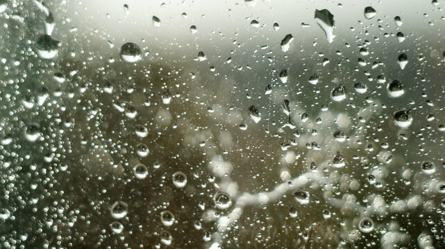 Raindrops on window glass surface as abstract moody background