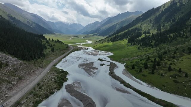 Aerial view of the winding river and road through the lush green valley of Chon Ashu Pass in Karakol, Issyk-Kul Region, Kyrgyzstan.