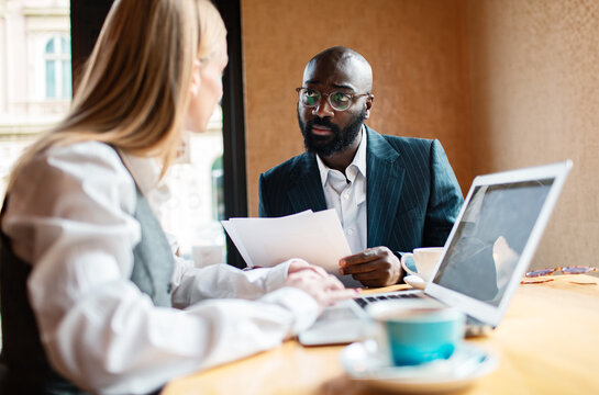 Business colleagues discussing paperwork at cafe table
