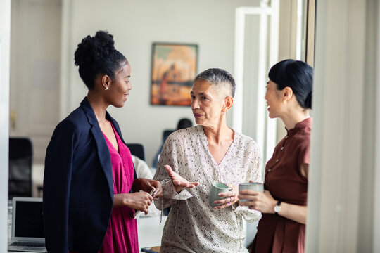 Diverse women colleagues chatting during a coffee break in modern office
