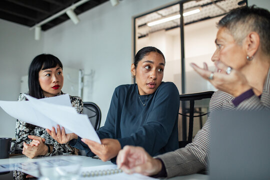 Diverse coworkers discussing documents in modern office meeting