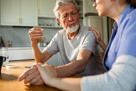 Caregiver helping senior man take medication at home