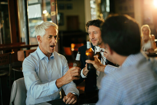 Business colleagues toasting beers after work at pub