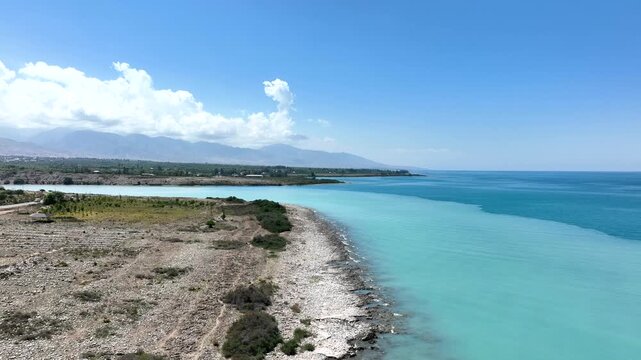 Aerial view of the turquoise waters of Issyk Kul lake along the rocky coastline of Cholpon Ata, Issyk-Kul Region, Kyrgyzstan.