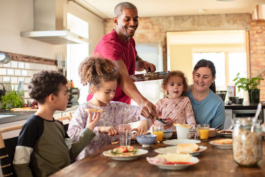 Parents and kids making breakfast together in the home kitchen
