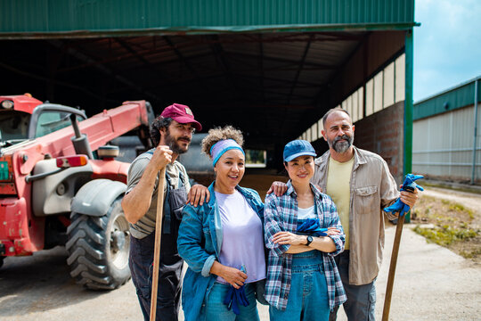 Team of farmers standing with tools at barn