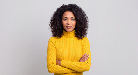 Obraz premium Portrait of a confident woman with curly hair wearing a yellow turtleneck isolated on white background