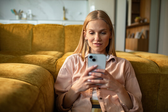 Young woman using smartphone on sofa in living room