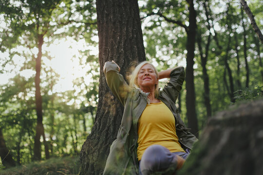 Senior woman relaxing outdoors in forest.