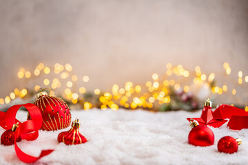 Naklejka premium A Christmas background featuring red baubles with golden glitter stripes, a star, and ribbon framing wide snowy ground, softly lit by warm twinkling lights with generous copy space.
