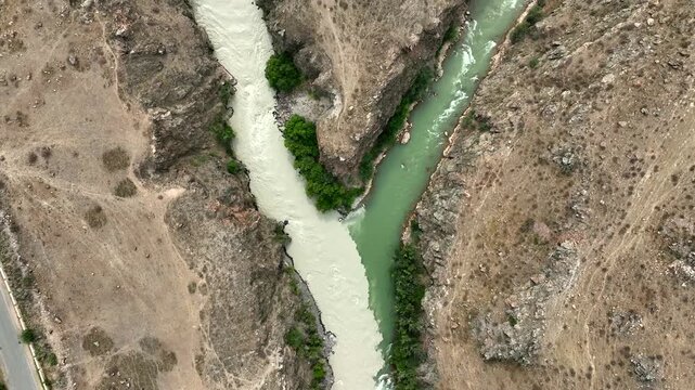Aerial view of the river confluence in Chong-Kemin National Park with contrasting water colors and rocky terrain in Shabdan, Chuy Province, Kyrgyzstan.