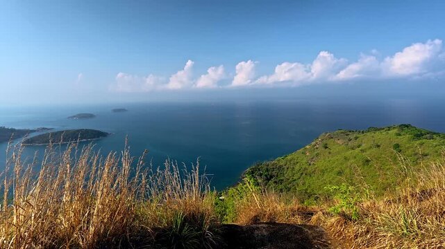 Sweeping panoramic view of the Andaman sea expanse with islands visible under the blue cloudy sky seen from Black Rock Viewpoint or Pa Hin Dum, a popular hiking trail in Phuket, Thailand