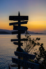 Wooden directional signpost with world cities at sunset by the sea © Mila