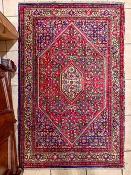 Antique Persian wool rug with diamond medallion on tiled floor