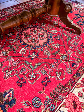 Persian wool rug under wooden table leg on tiled floor