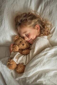 Peaceful child hugging her favorite soft toy while dreaming and smiling in a cozy bed at home