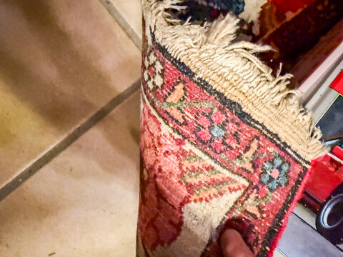 Folded edge of antique Persian wool rug with fringe