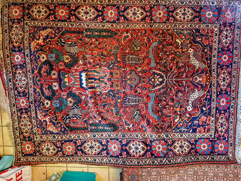 Antique Persian wool rug with tree of life on tiled floor