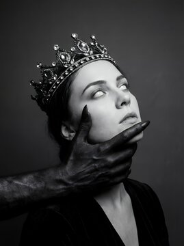 Dark fantasy book cover concept of a cursed queen with white eyes and an ornate crown held by a demonic black hand, black and white gothic horror portrait