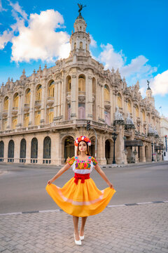Young latina woman portraying La Catrina with traditional skull makeup and colorful dress, celebrating Mexican culture and folklore in front of a historic building in Havana