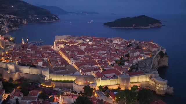 Dubrovnik, Croatia. Aerial 4K night panoramic drone view of the peninsula with the old medieval town, harbor and Adriatic cityscape. Majestic view of the medieval town, ancient fortress and resort.